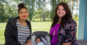 Young mom sits with her child next to a clinician in a park