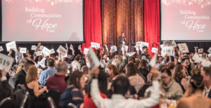 Room filled with people with bid cards up in air